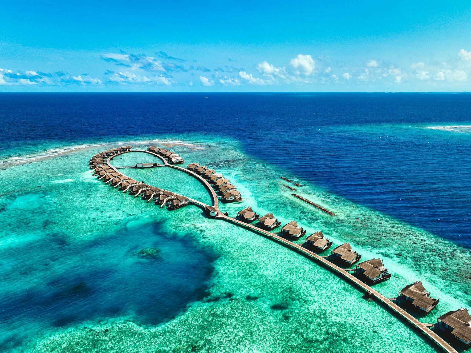 An aerial view of overwater villas and a turquoise lagoon in the Maldives